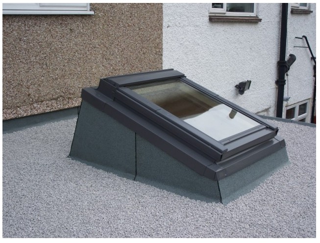 A Velux window and adapter on a flat roof.